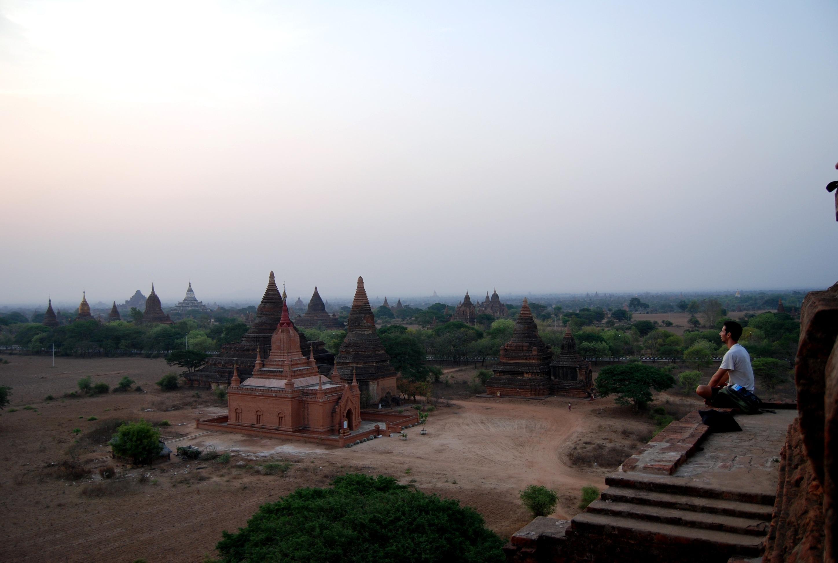 Brett Engle seated on ancient temple ruins overlooking the pagodas of Bagan, Myanmar at dusk