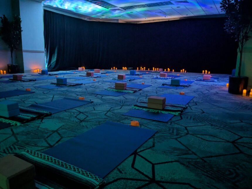 Conference ballroom set with yoga mats, blocks and candles under blue ambient lighting