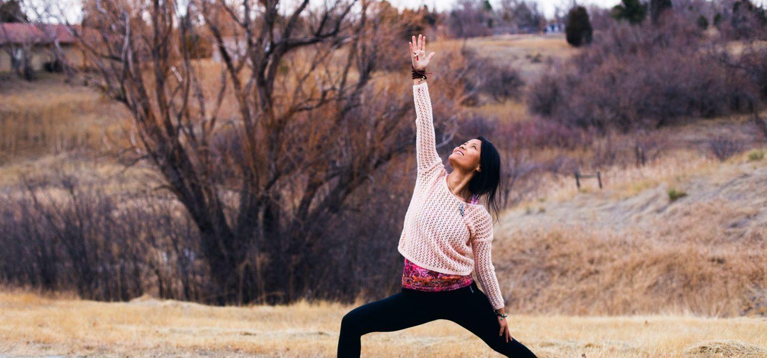 Penpa Dolma in a warrior yoga pose in an open dry field