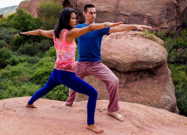 Brett Engle and Penpa Dolma in warrior pose together on the red rocks