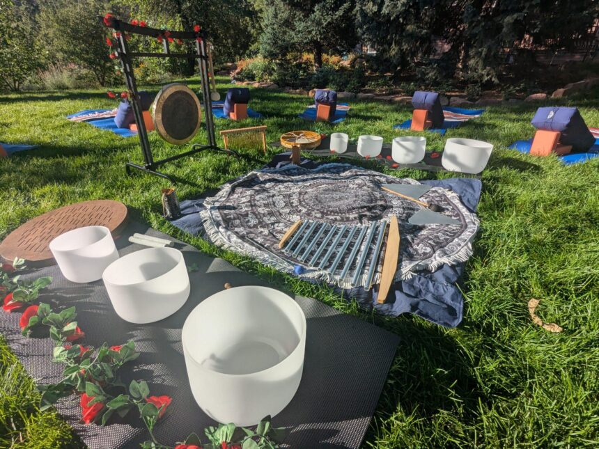 Outdoor sound bath setup with crystal singing bowls and gong on the grass