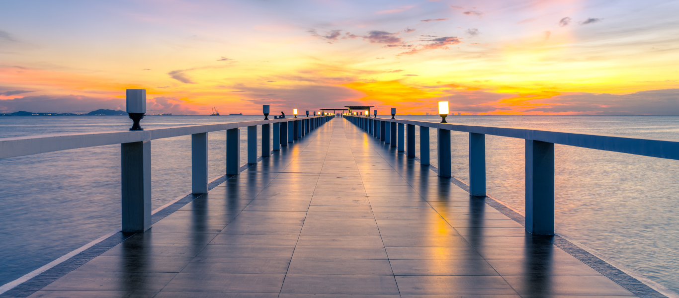 Seaside pier stretching toward the ocean at a vivid sunset