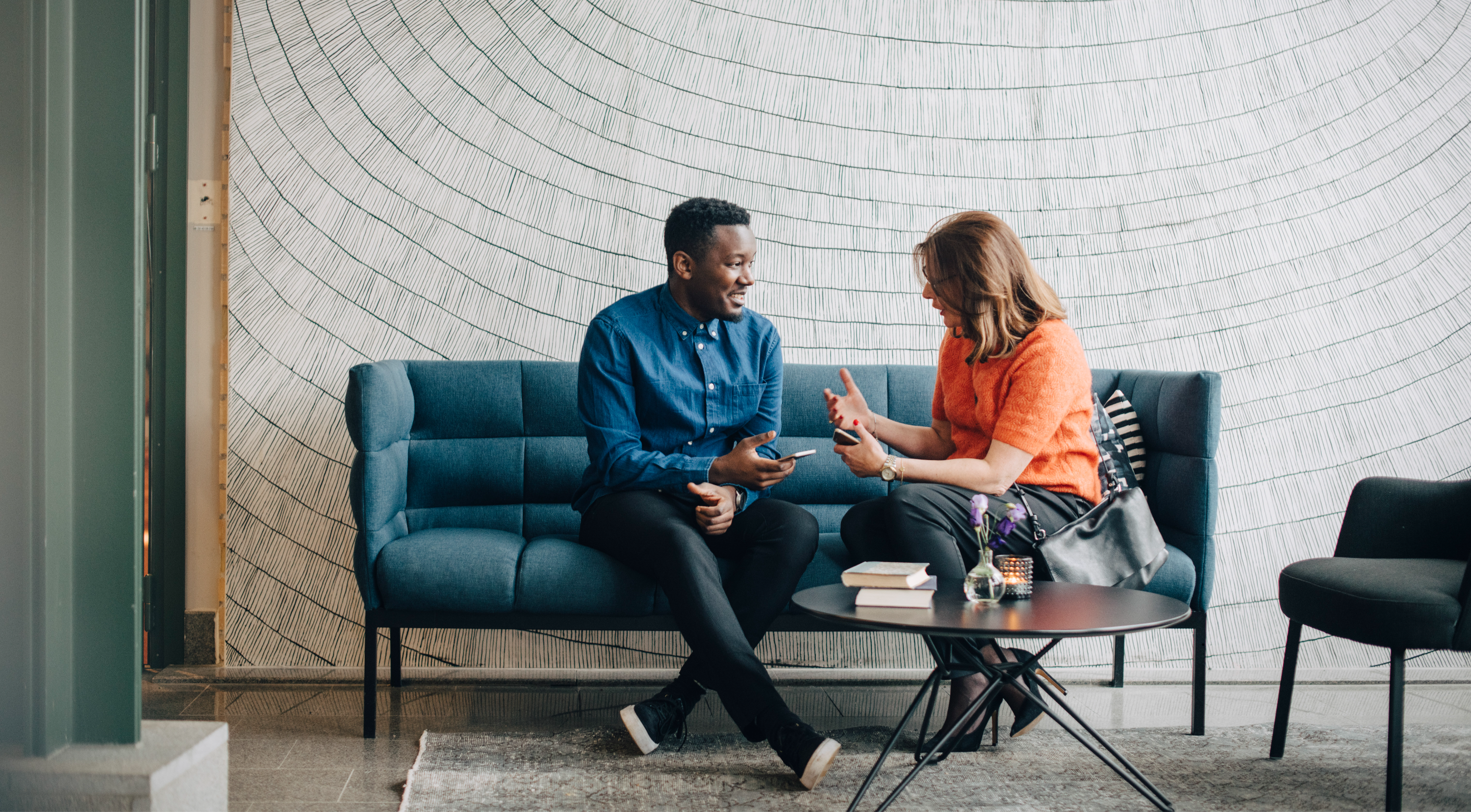 Two professionals in conversation on a sofa during a coaching session