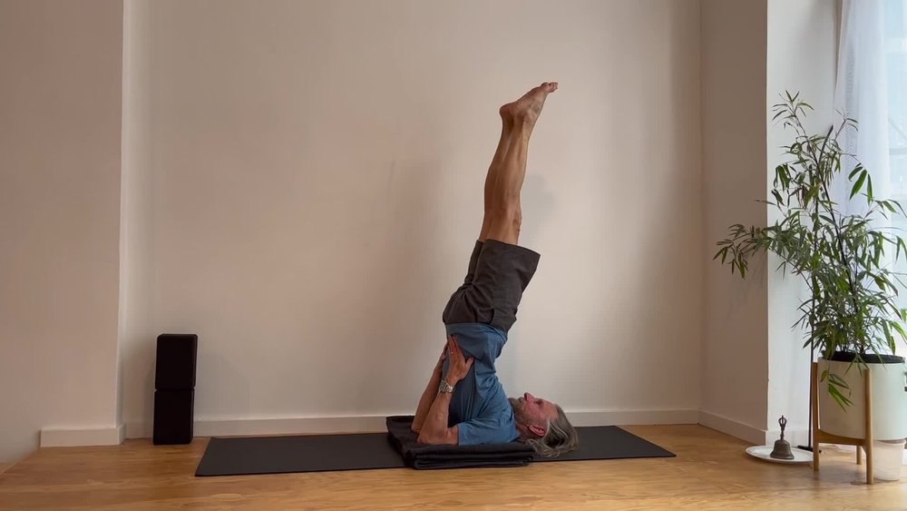 A practitioner in shoulder stand pose on a mat