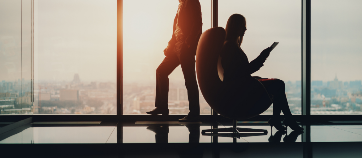 Two professionals in a high-rise office at sunset