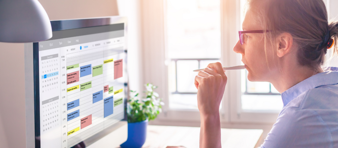 Woman with glasses viewing a calendar on a monitor