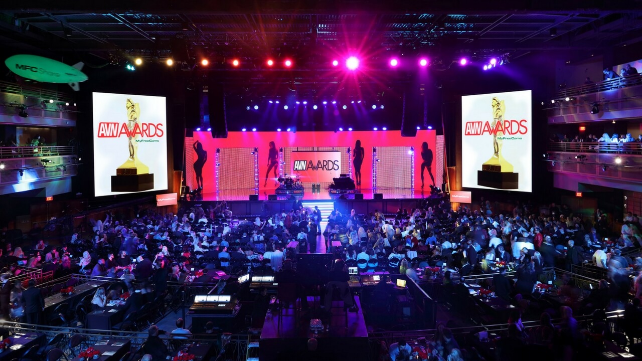 Wide shot of AVN Awards ceremony stage with LED screens, silhouette dancers, and full audience