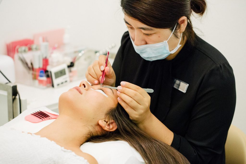 Technician applying lash extensions with tweezers