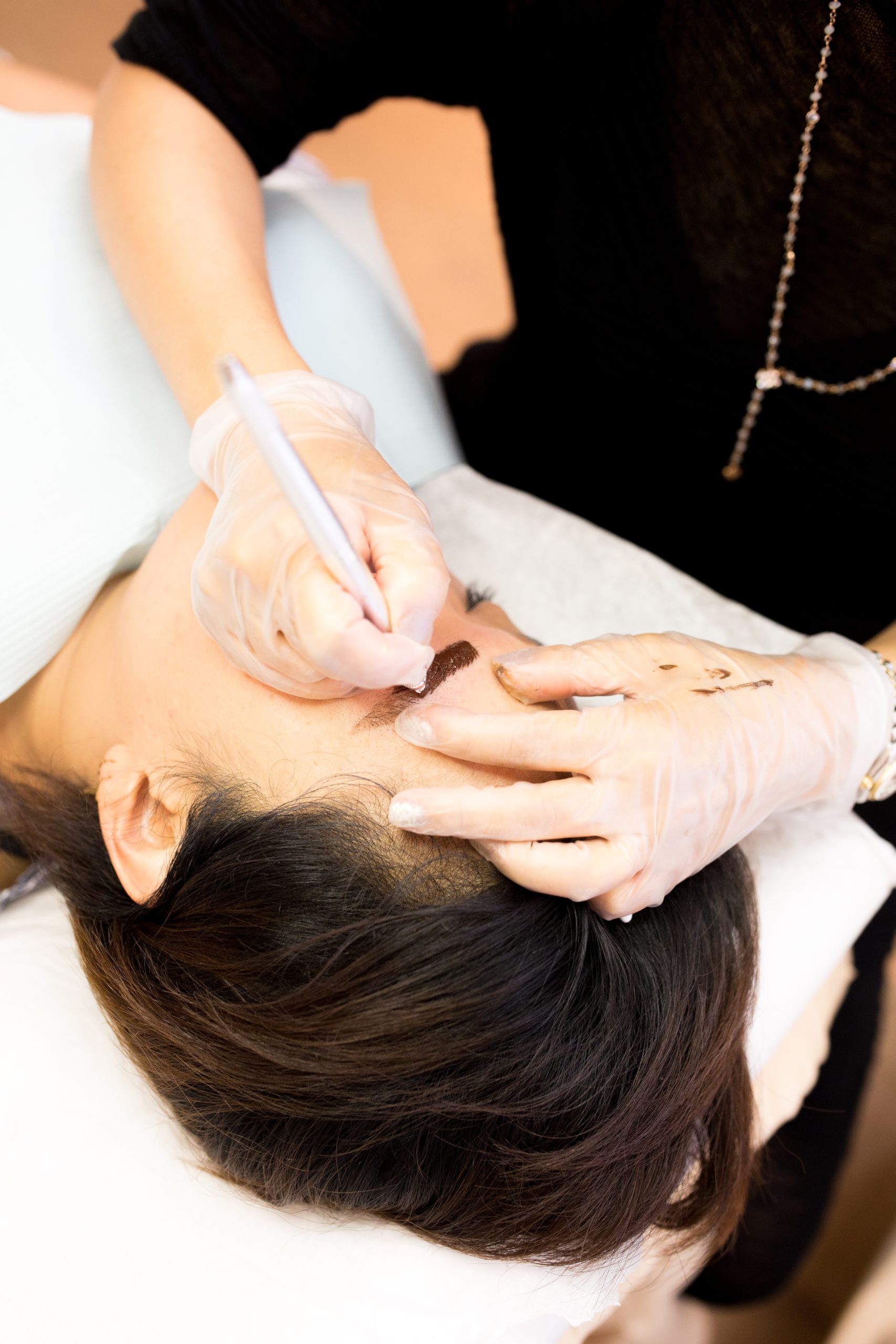 Technician applying semi-permanent brow makeup