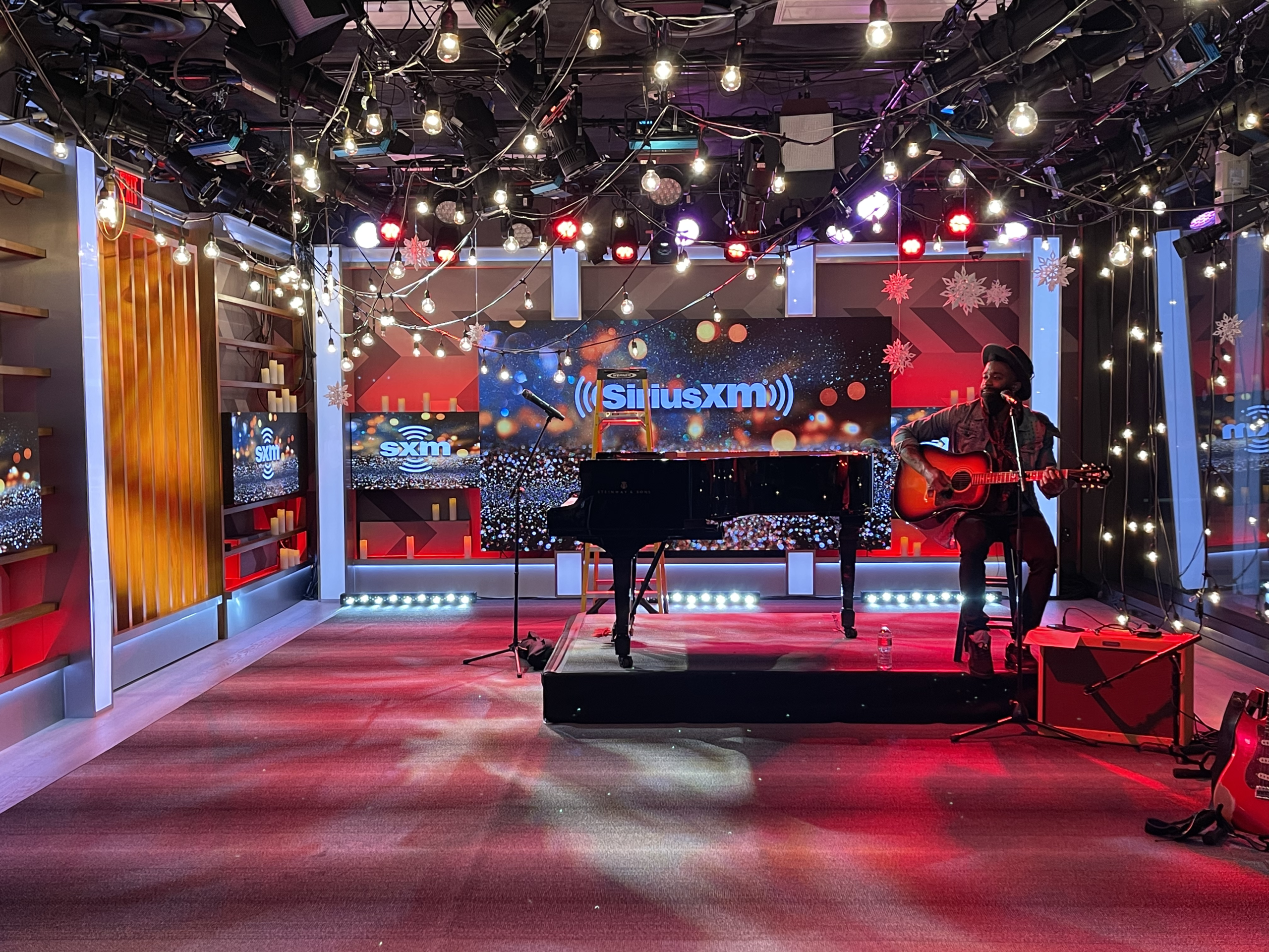 SiriusXM studio interior with a musician performing on a holiday-decorated stage