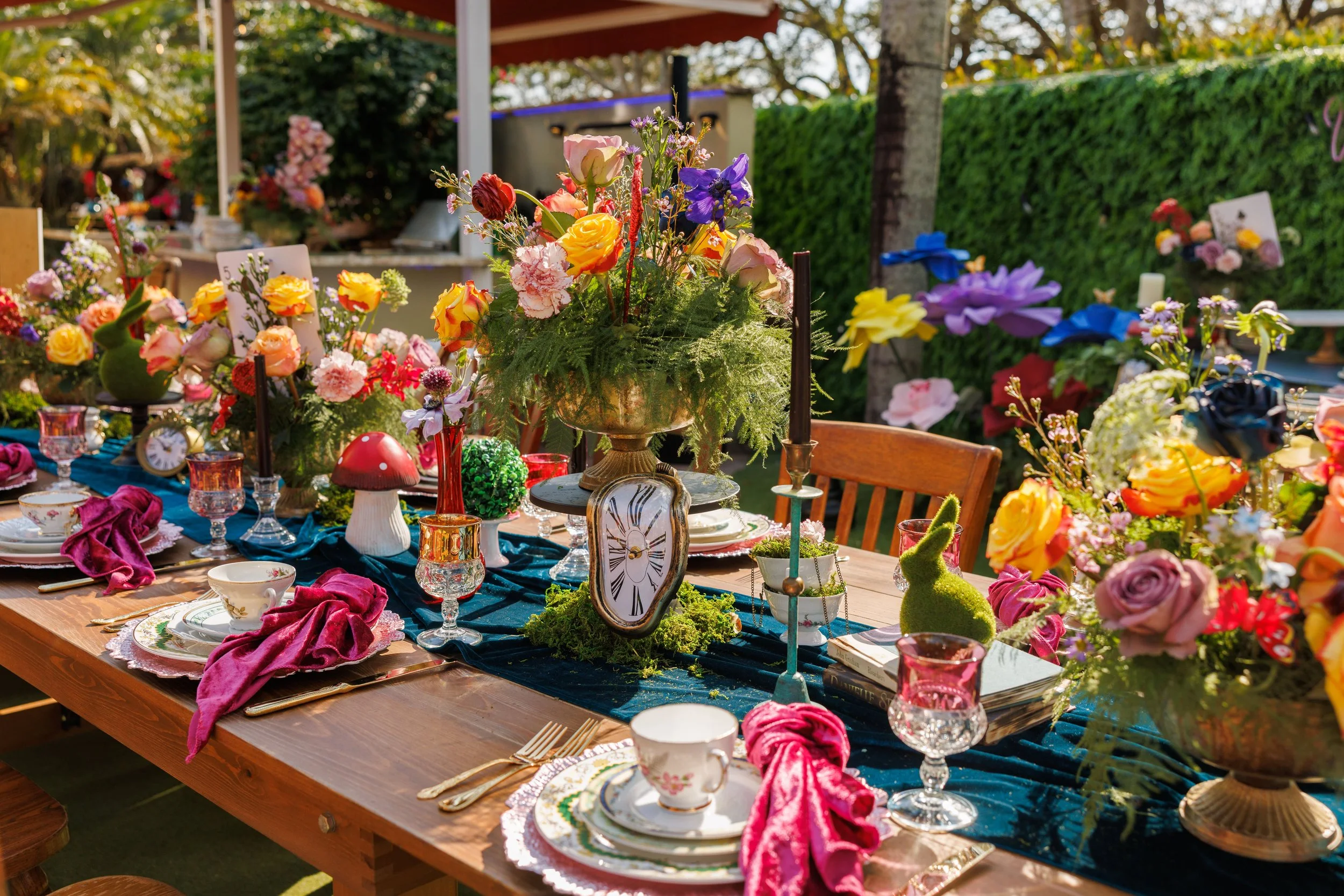 Alice in Wonderland tablescape with teacups, a melting clock and a Cheshire cat backdrop