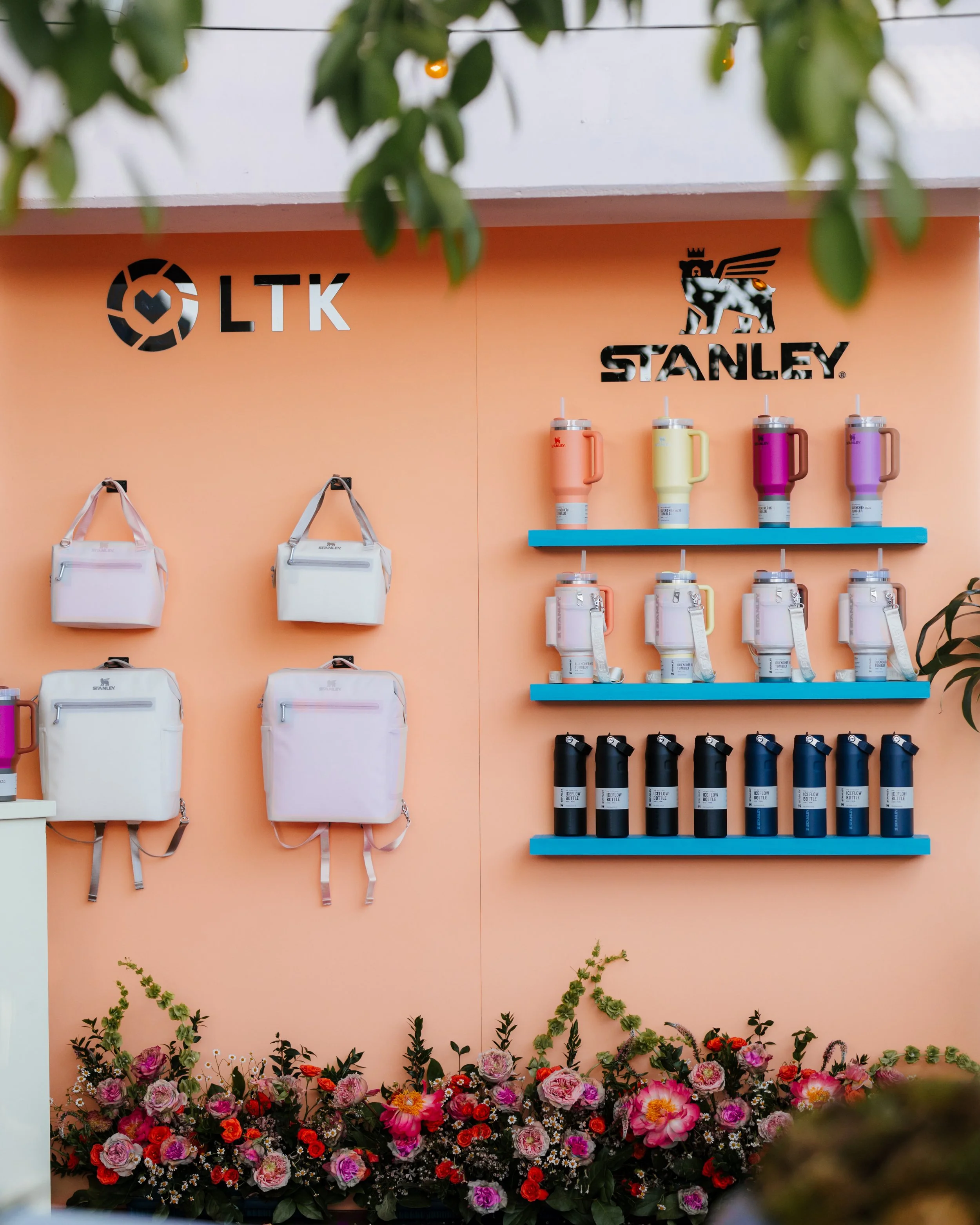 Stanley product wall with tumblers and bags on a peach wall with a floral border