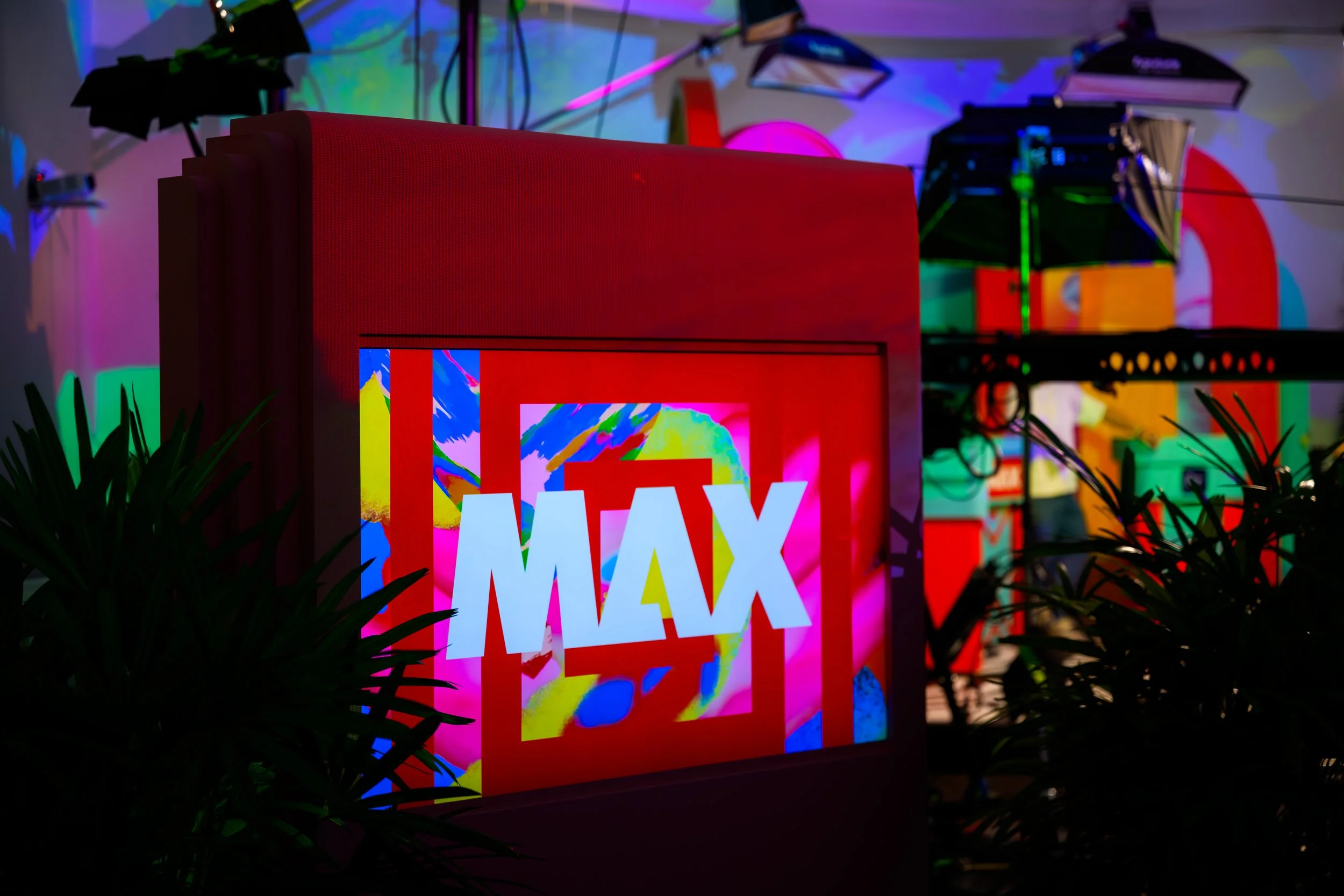 Illuminated red MAX light box surrounded by tropical plants and coloured lighting