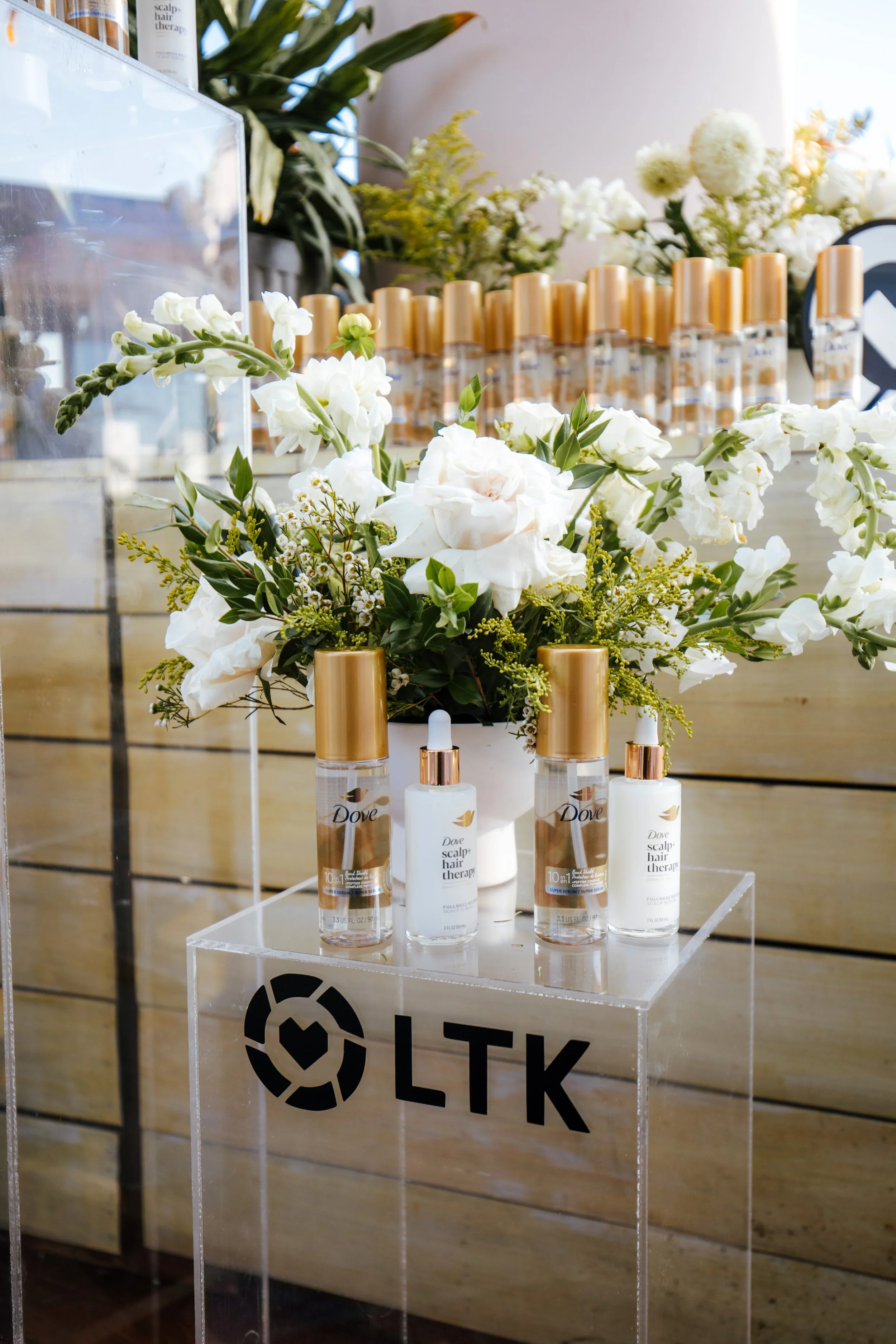 Dove product display on an acrylic pedestal with a white floral arrangement