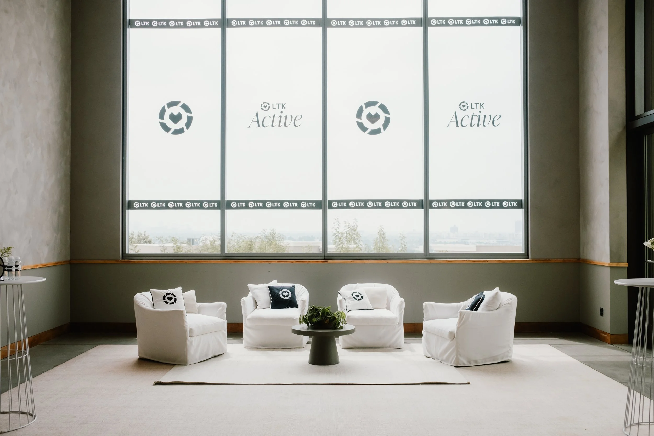 Branded lounge area with white armchairs, navy pillows and LTK Active window graphics