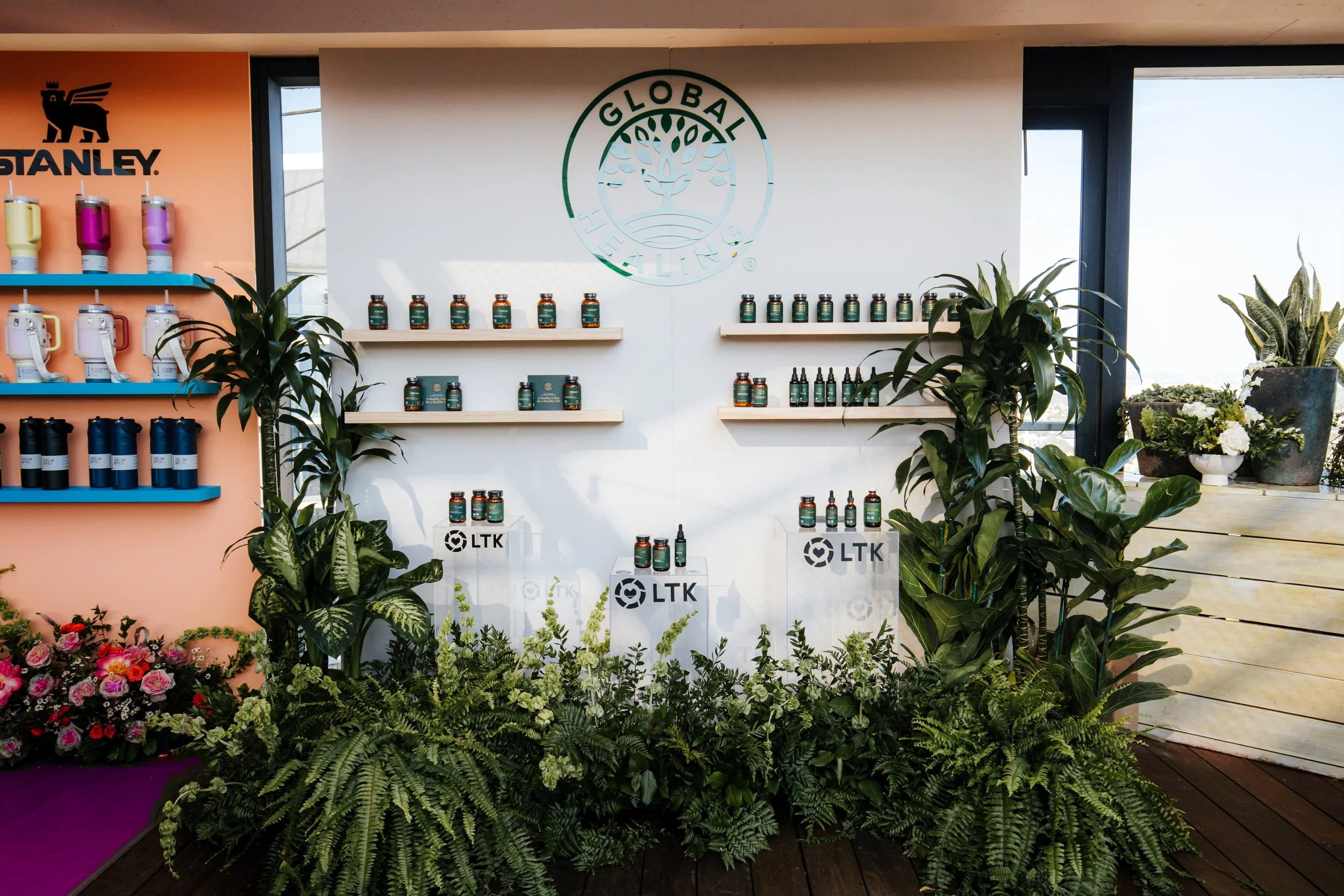 Global Healing supplement display wall built into a greenery installation