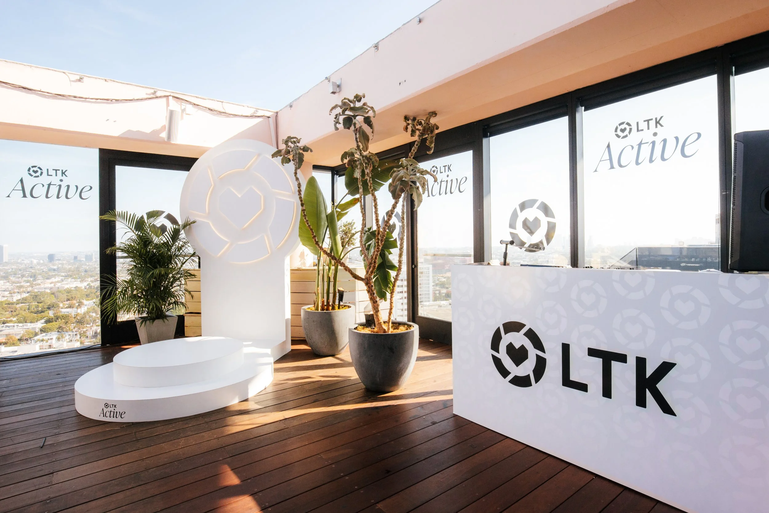 LTK Active rooftop party with a white LTK logo sculpture, branded reception desk and skyline view