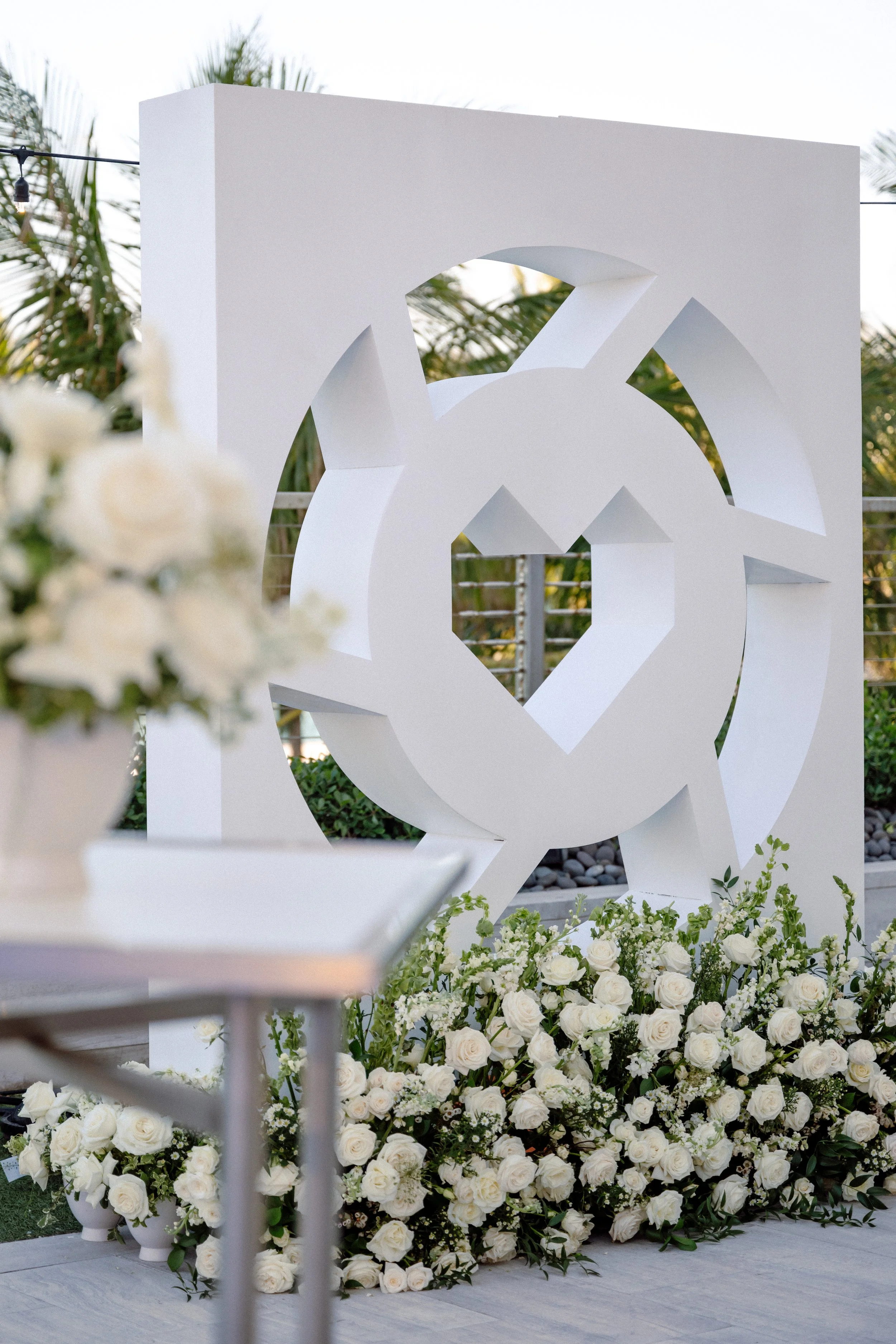 Large white sculptural LTK logo installation dressed with white roses and greenery