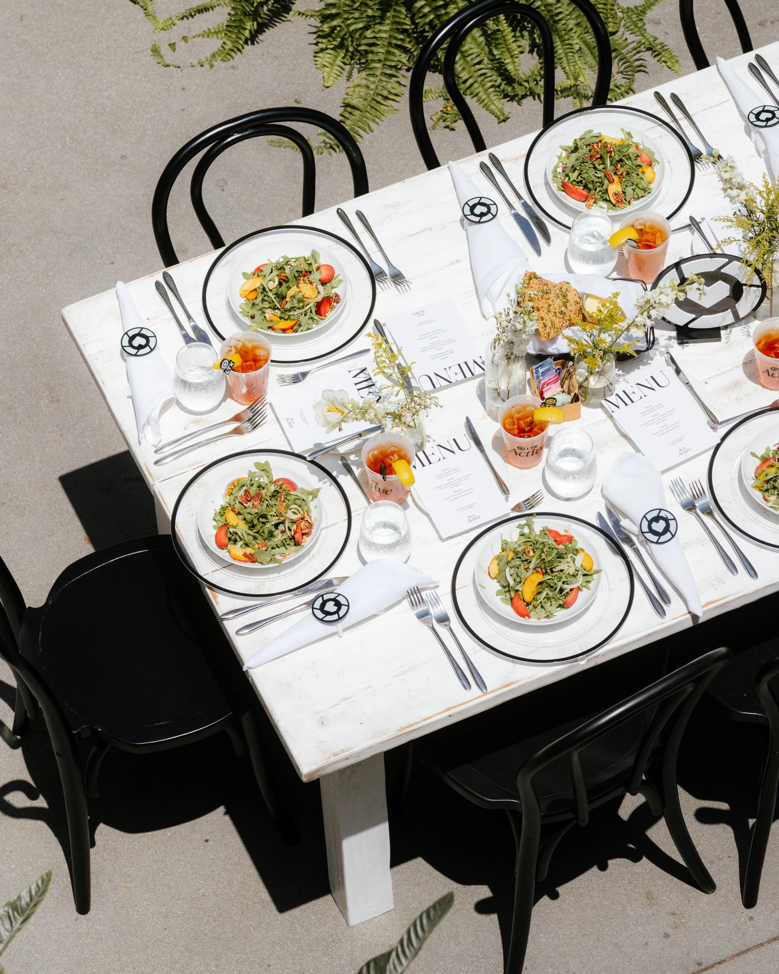 Overhead view of a farm table with branded placemats, salads and floral centrepieces