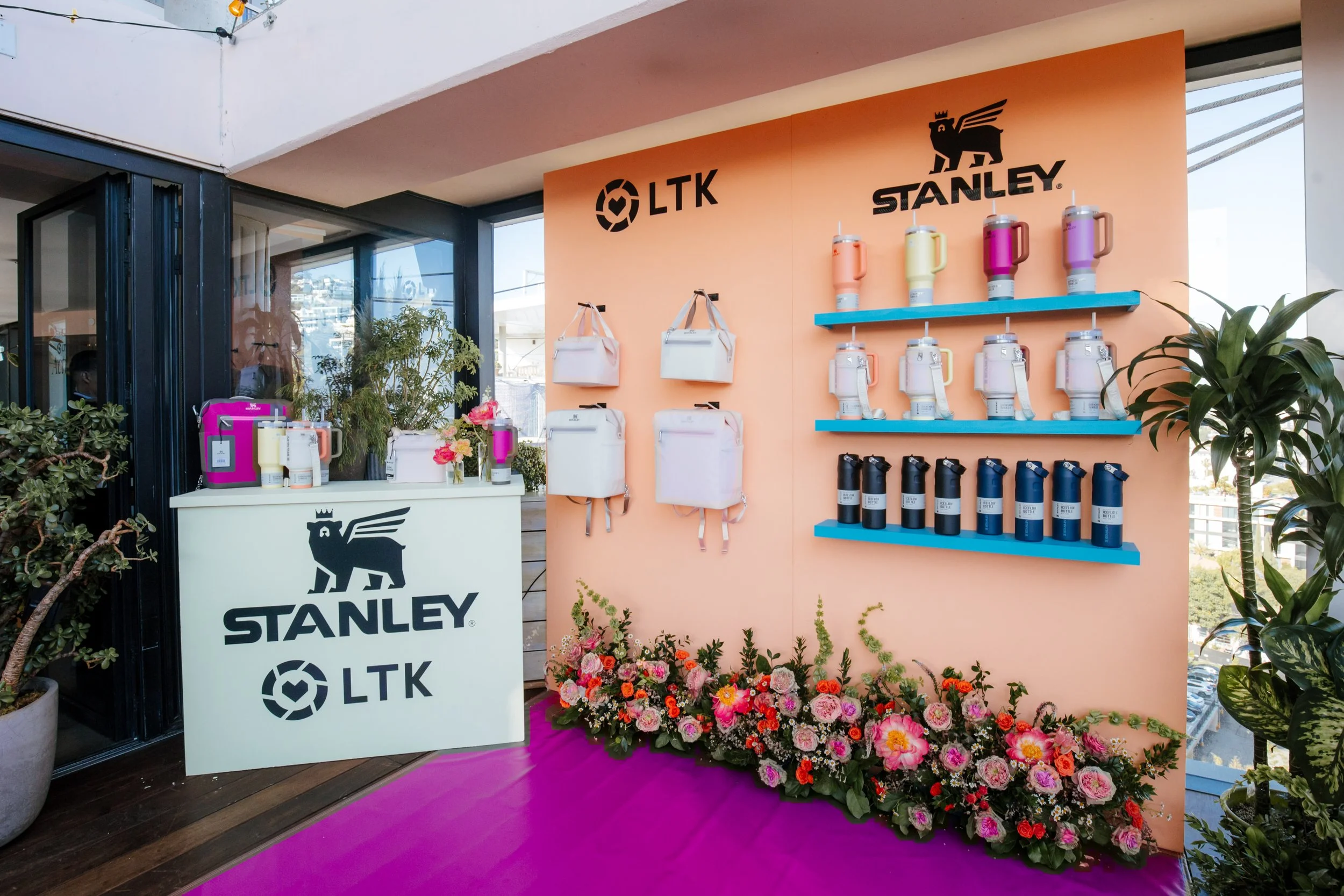 Stanley and LTK product wall on a peach wall above a pink carpet