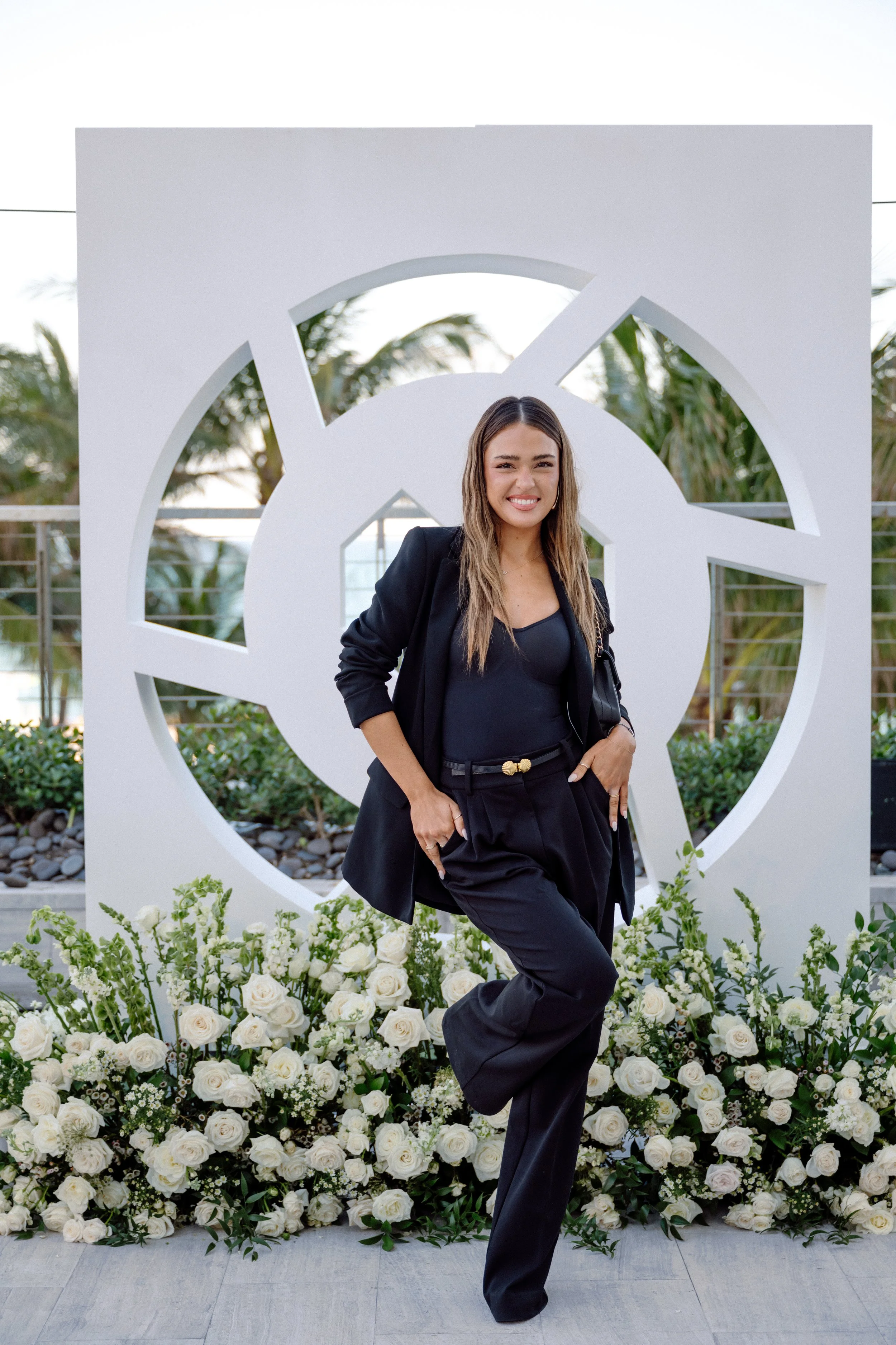 Woman in a black suit in front of the giant white LTK logo sculpture dressed with white roses
