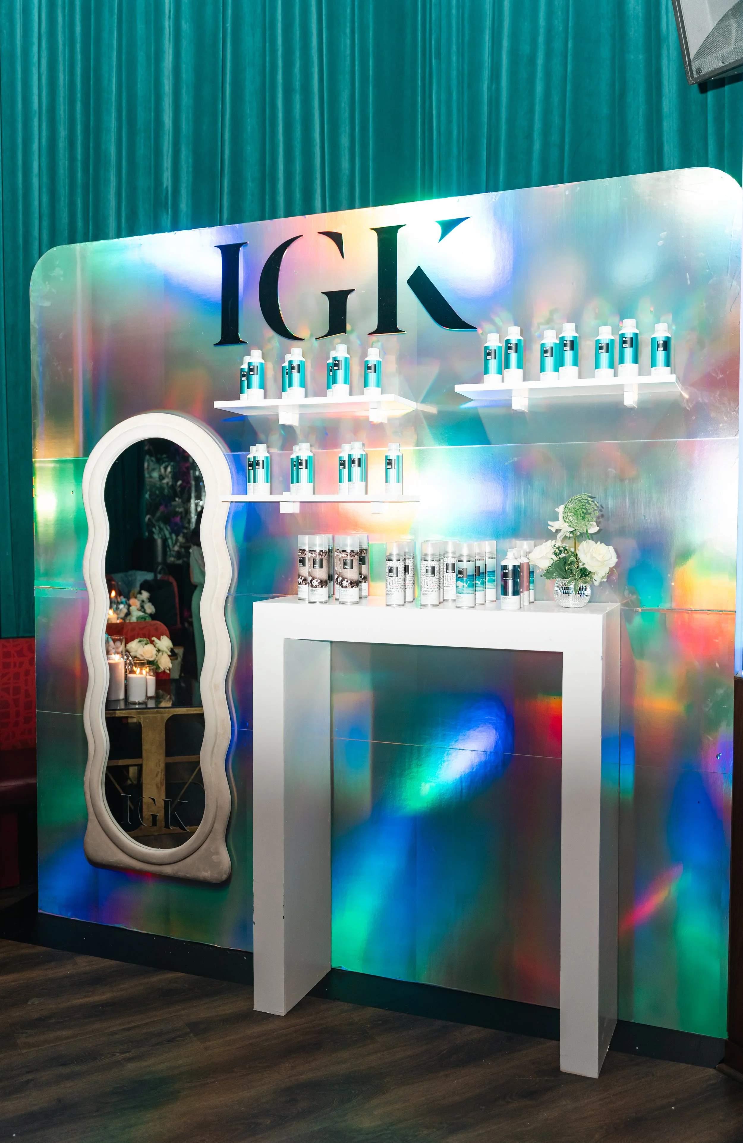 IGK product booth with holographic backdrop, blue bottles and a wavy mirror