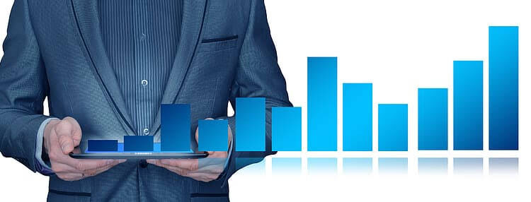 Businessman holding a tablet showing a rising 3D bar chart