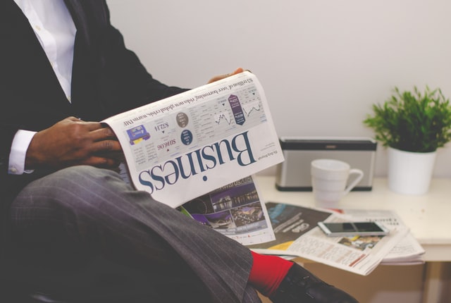 Person in a suit reading a business newspaper