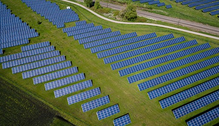 Aerial view of a large solar panel farm on green fields