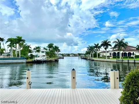 Waterfront canal view from a dock lined with luxury homes and palm trees at 2450 Tarpon Road, Naples