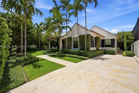 White single-story luxury home with tropical garden and stone driveway at 265 Stewart Drive, Merritt Island