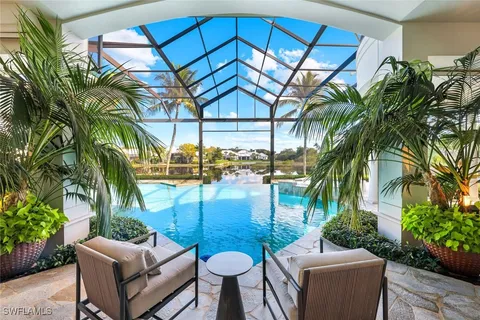 Screened pool area with lounge chairs and water view at 27241 Ibis Cove Court, Bonita Springs