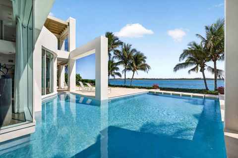Modern white luxury home with infinity pool overlooking a tropical bay at 7034 Se Harbor Circle, Stuart