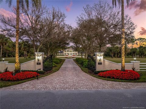 Gated estate driveway at dusk with illuminated pillars at 5551 Sw Mistletoe Lane, Palm City