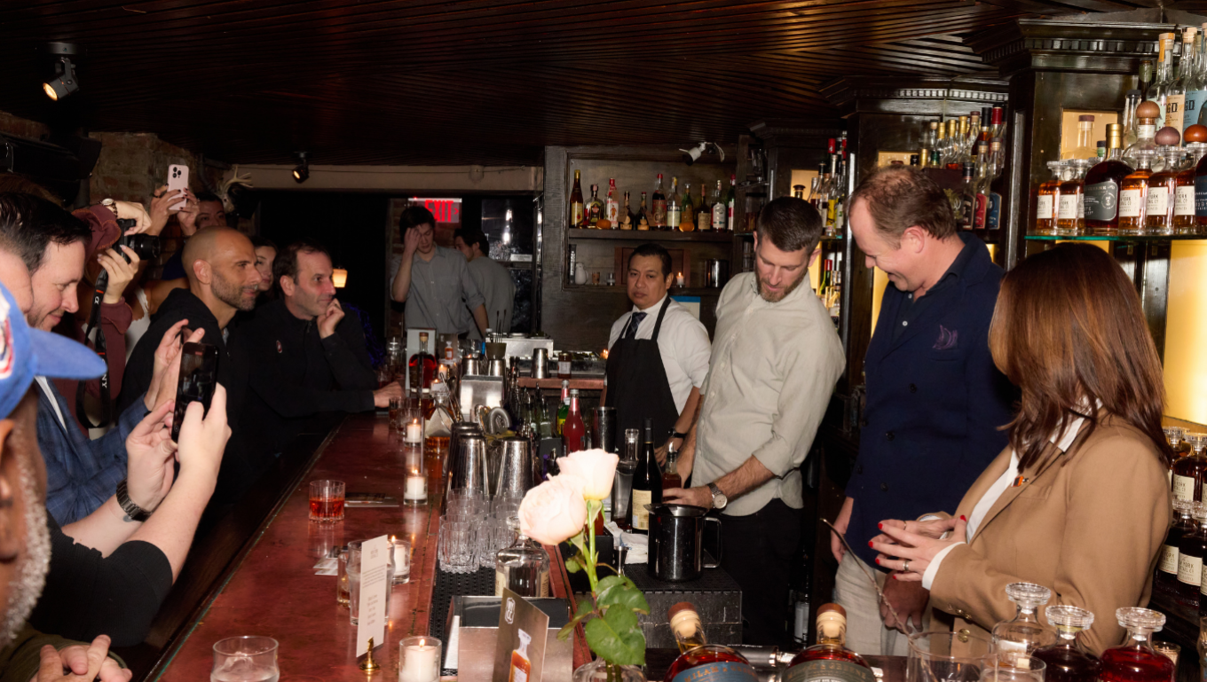 Crowded bar with guests watching bartenders mix cocktails at the New York Cocktail Co. launch
