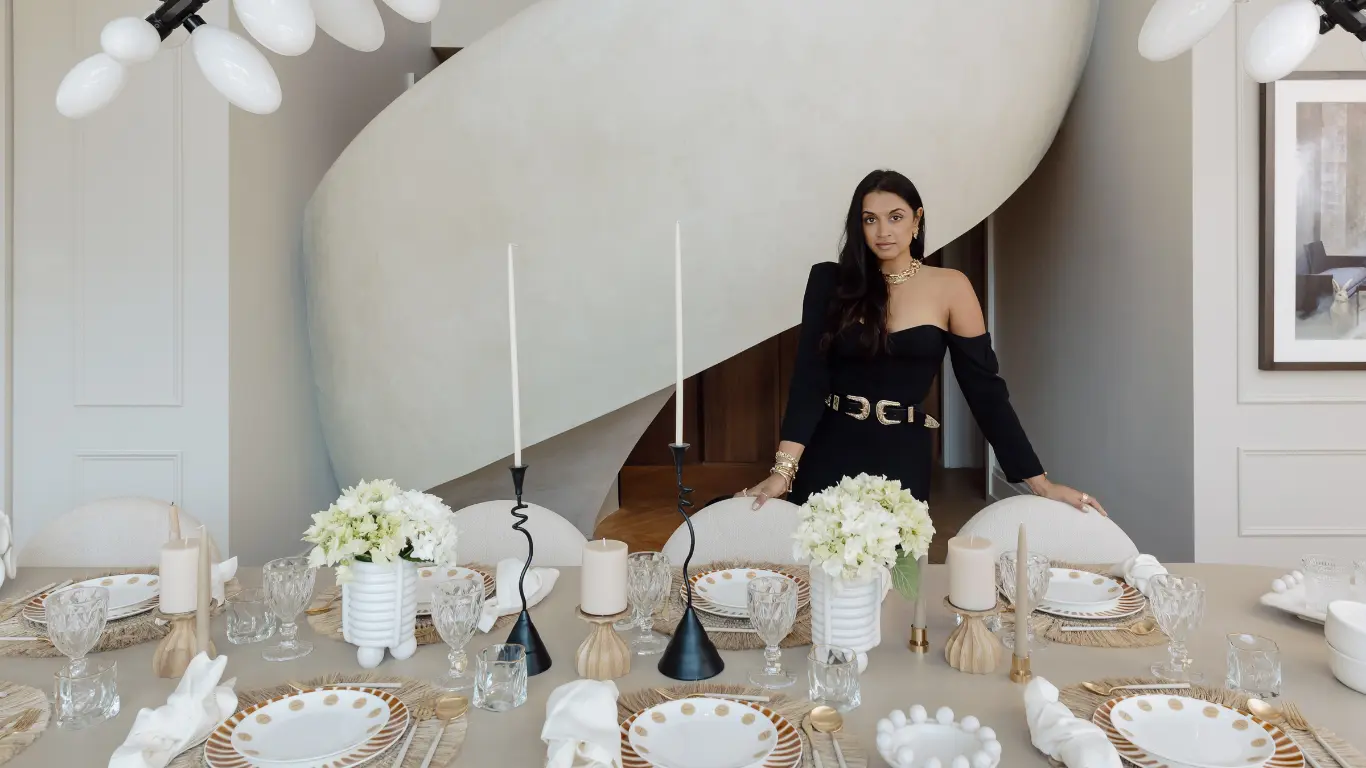 Woman in a black off-shoulder top at an elegantly set dining table with candles and flowers — Revelry
