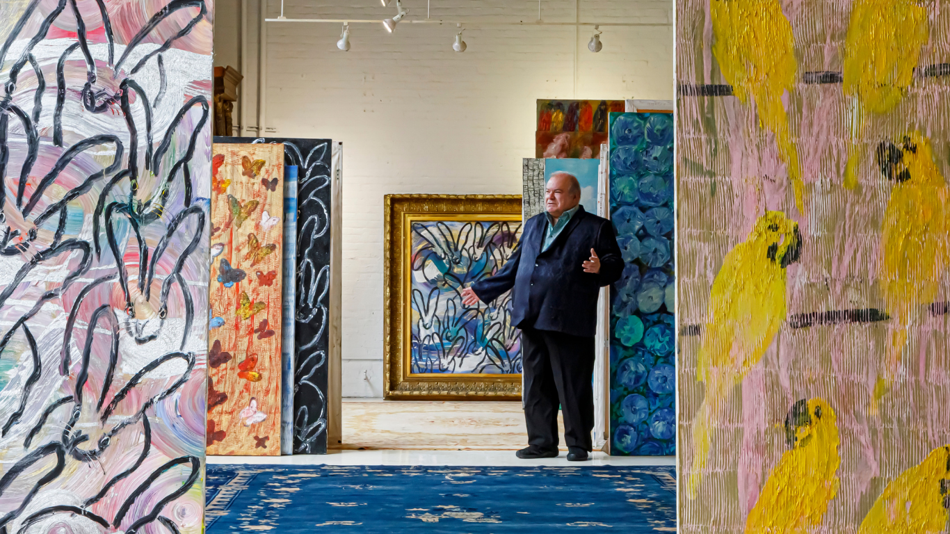 Man in a navy blazer among large colorful paintings in an art studio — Hunt
