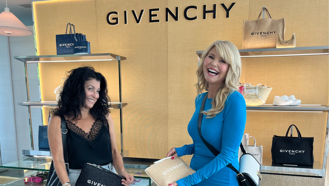 Two women laughing inside a Givenchy boutique holding branded bags