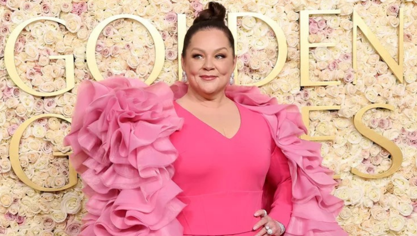 Woman in a hot-pink ruffled gown at the Golden Globes floral step-and-repeat — With Clarity
