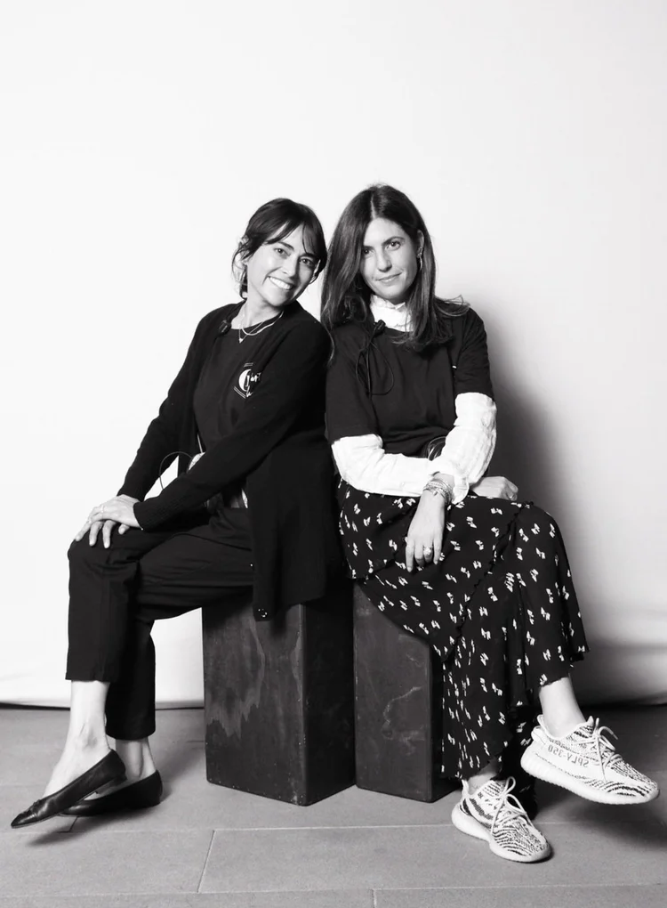 Black and white portrait of the two LA Party Stylists founders seated on blocks, smiling