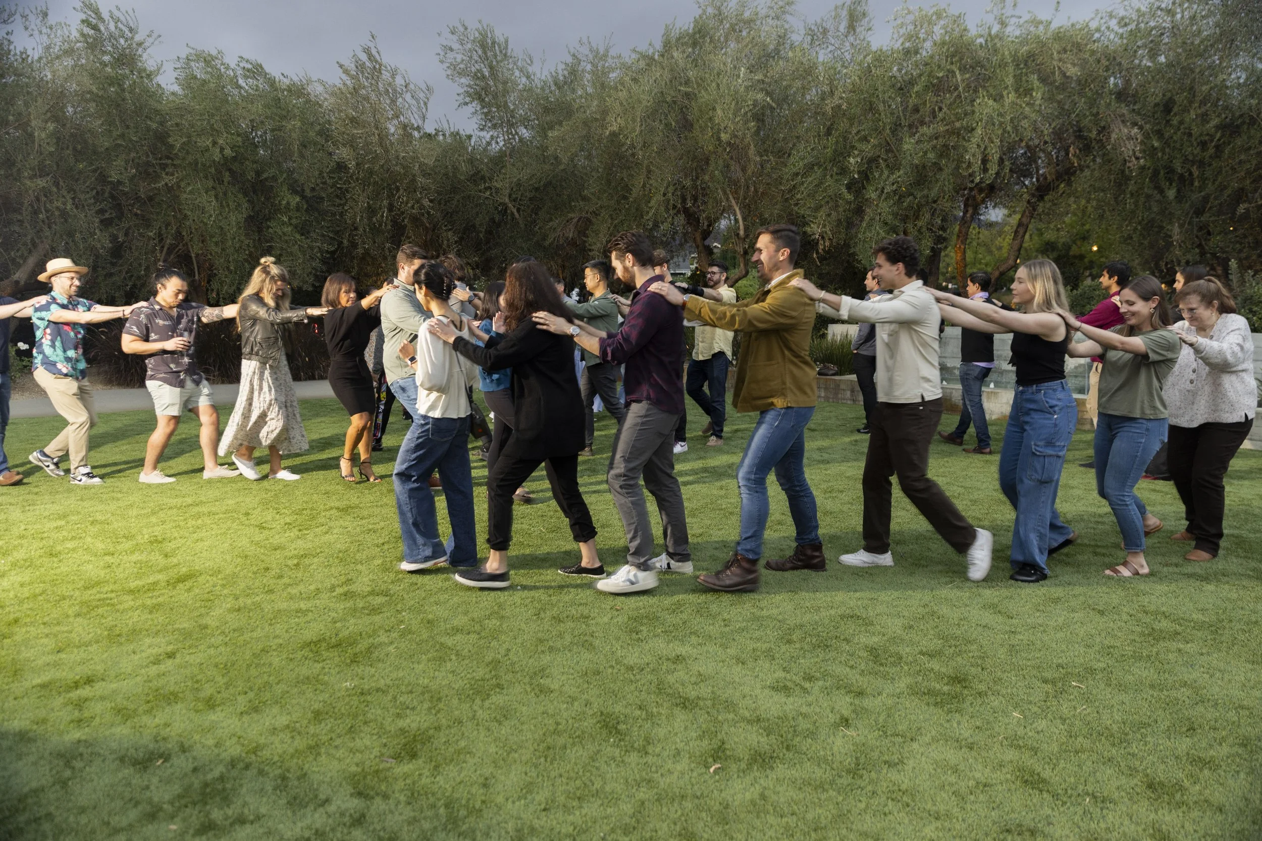 Large group of employees linked in a chain line during an outdoor Laughing and Development workshop