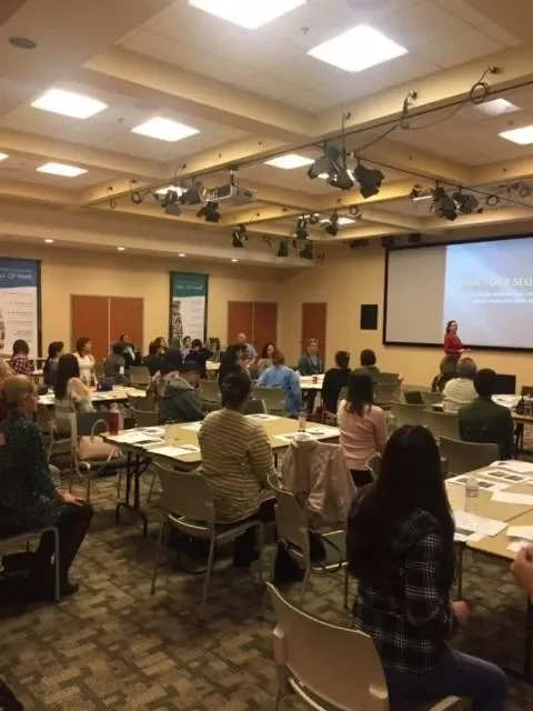 Lauren Polly speaking at a corporate healthcare event on patient-caregiver communication and human connection.