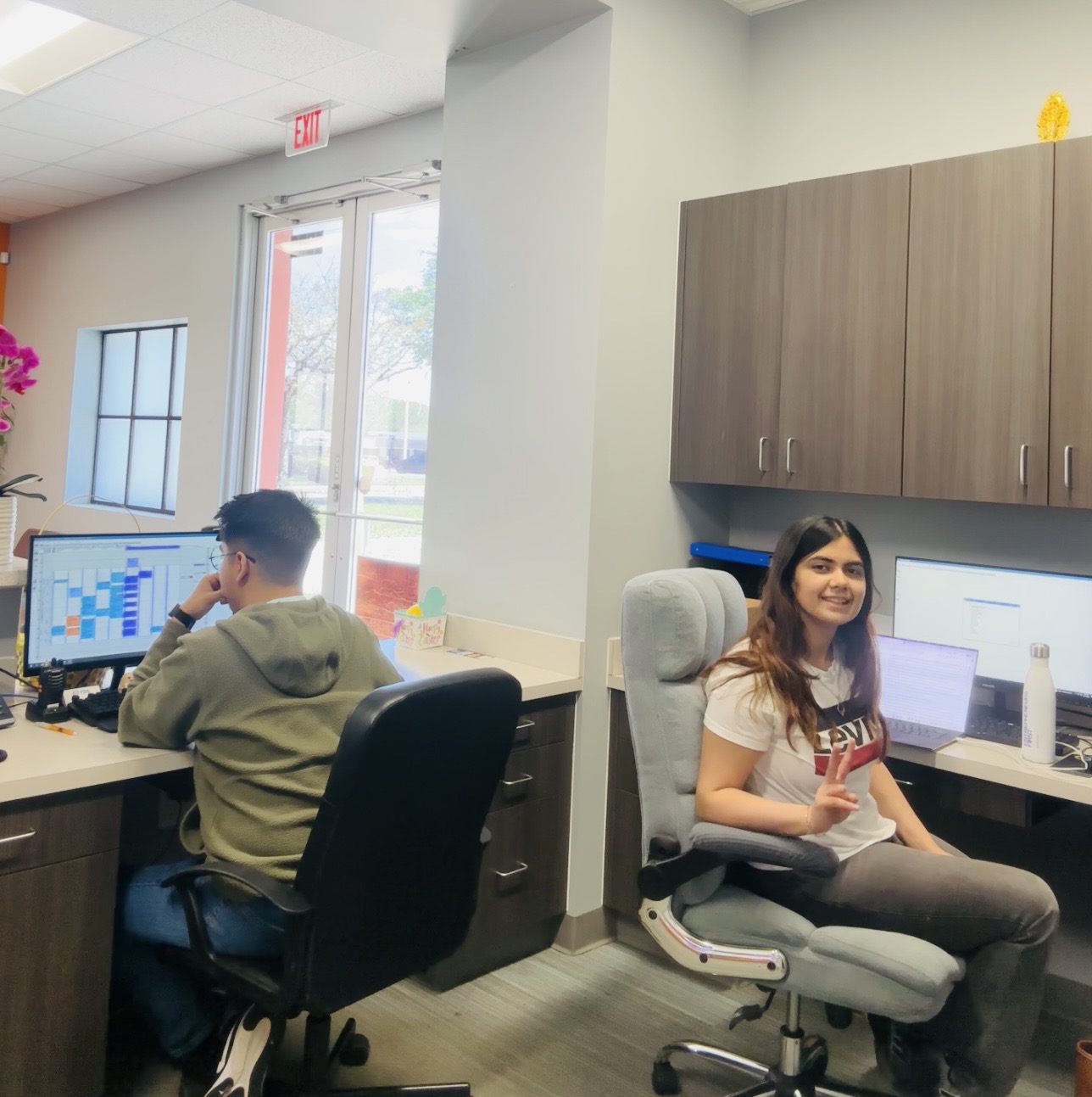 Two people working at desks in a dental office admin area