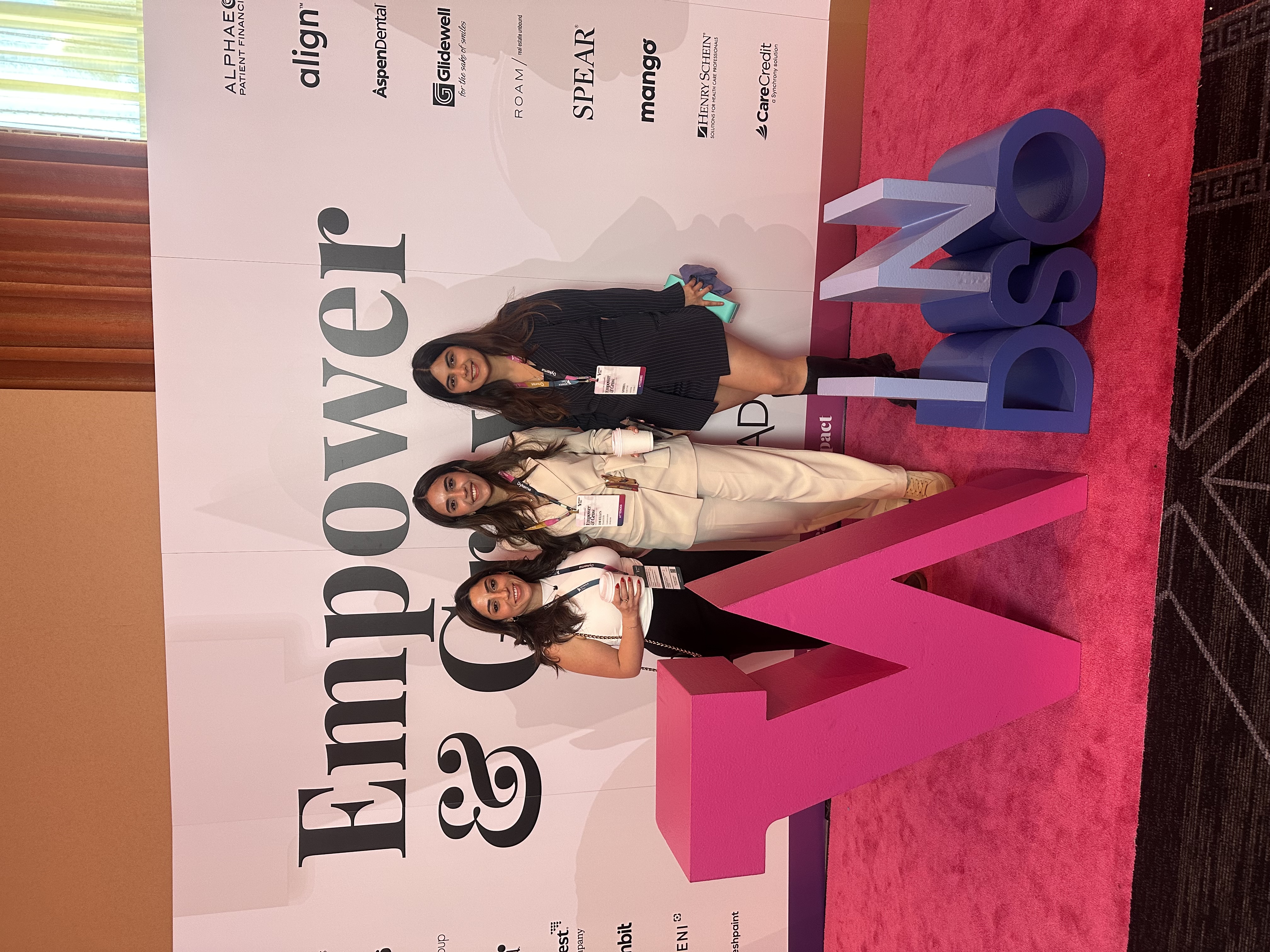 Three women at the Empower and Grow NDSO conference backdrop