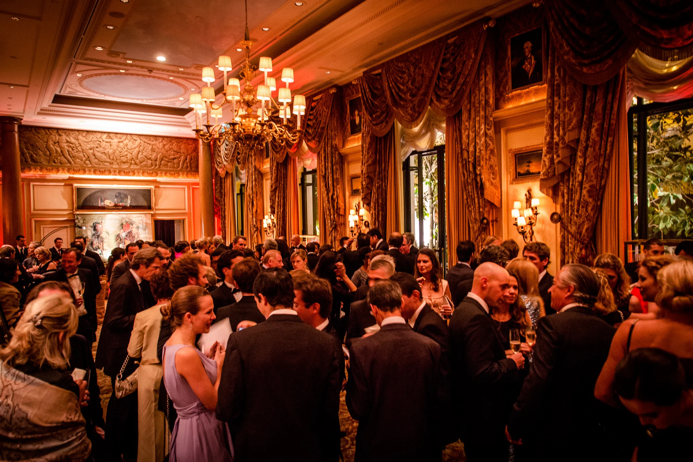 Black-tie gala reception in an ornate ballroom with chandeliers