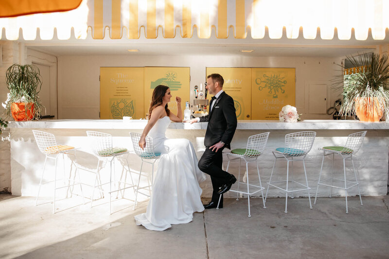 Couple at a retro Palm Springs bar with a yellow awning and wire barstools — Laura and Kevin