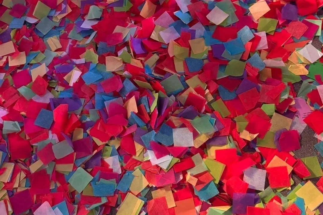 Close-up of colourful confetti pieces spread across a surface