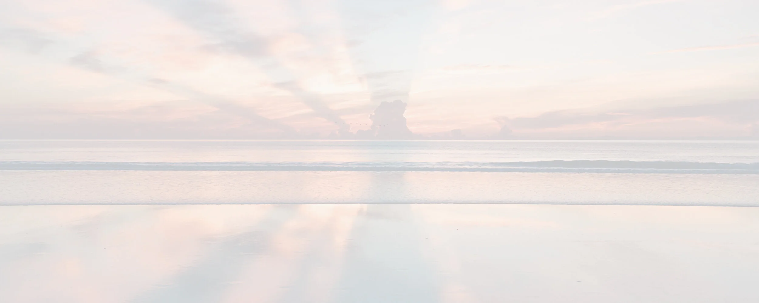 Pale pastel ocean horizon with soft pink clouds reflected on wet sand