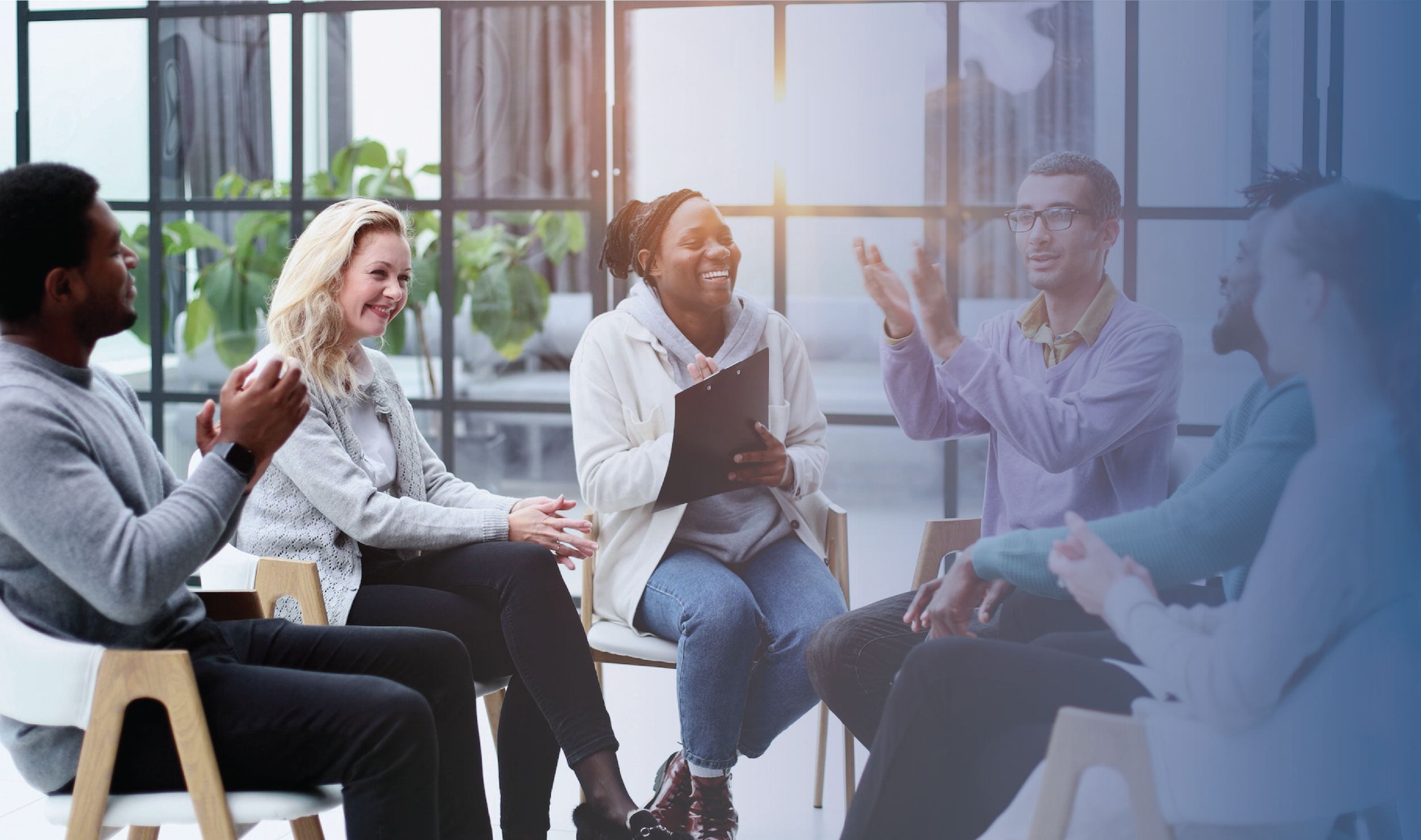 Diverse group of professionals laughing together in a circle in a bright office