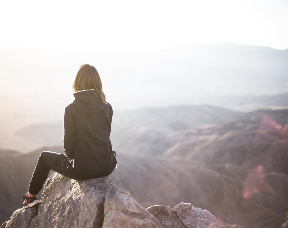 Woman on a rock ledge overlooking mountains